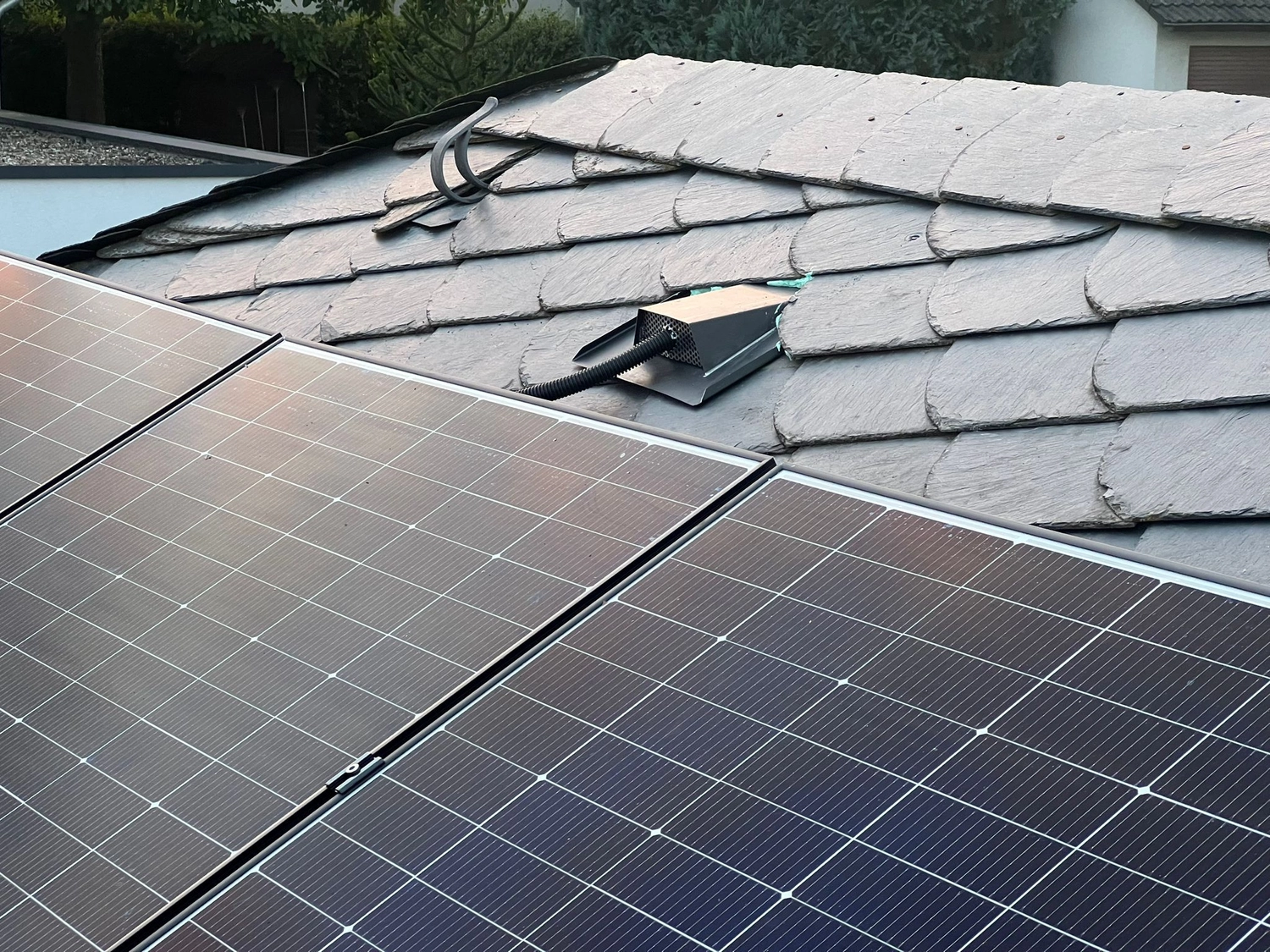 Ljus Volt - Photovoltaiklösungen - Modernes Haus mit blauen Sonnenkollektoren auf dem Dach. Ende des Tages, Sonnenuntergang. Idyllische Atmosphäre.